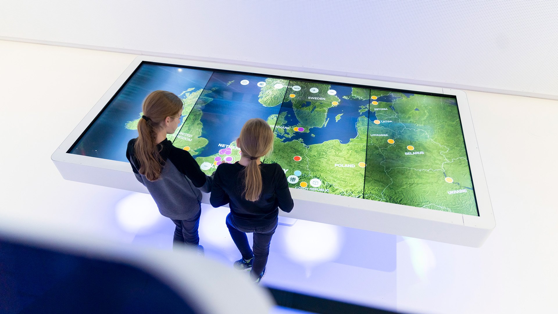 People interacting with a large digital map display