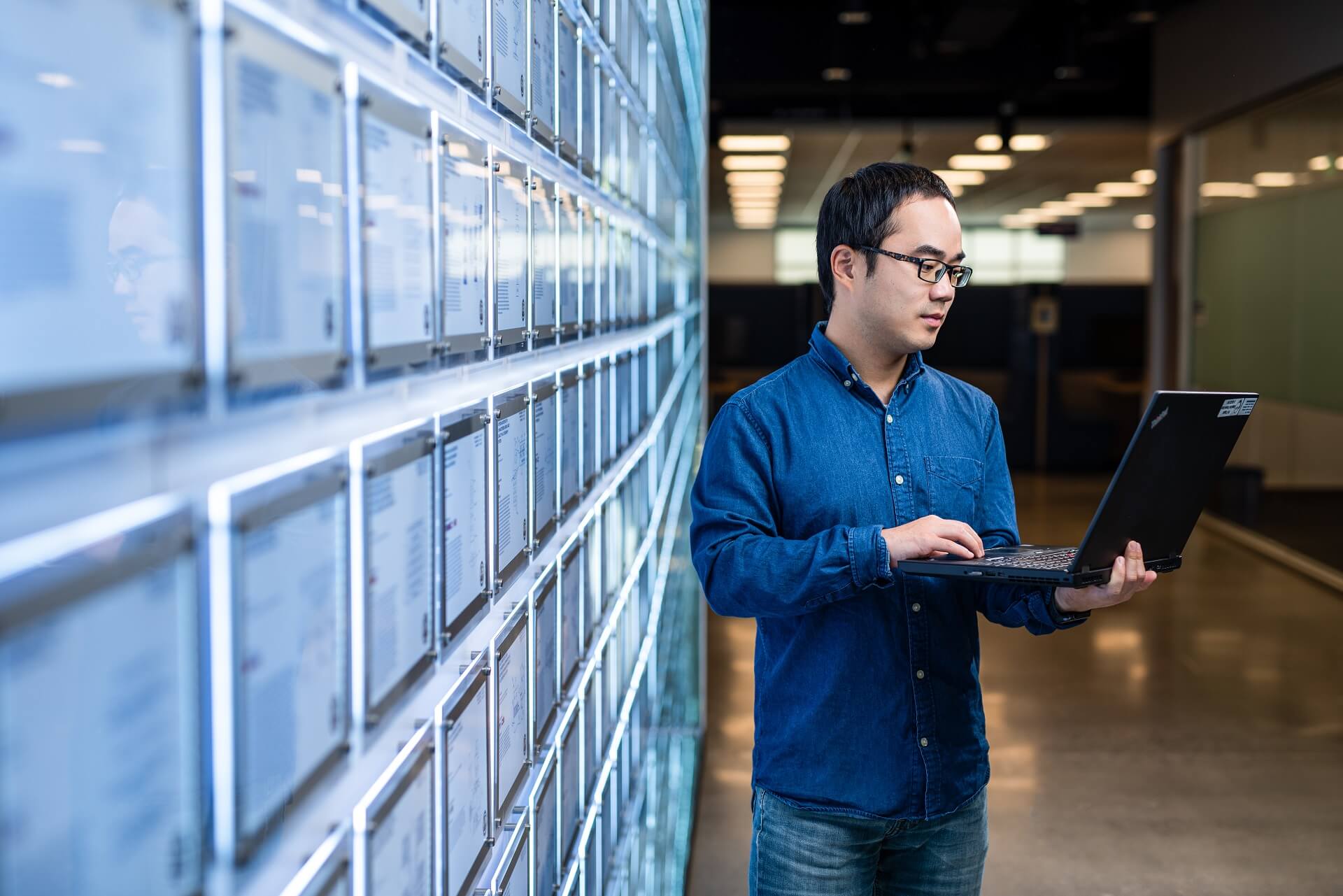 An ASML employee works on his laptop by a wall covered in patents An ASML employee works on his laptop by a wall covered in patents